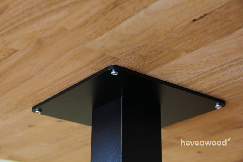 Detail horní desky černé podnože se šroubem pod dřevěnou stolovou deskou